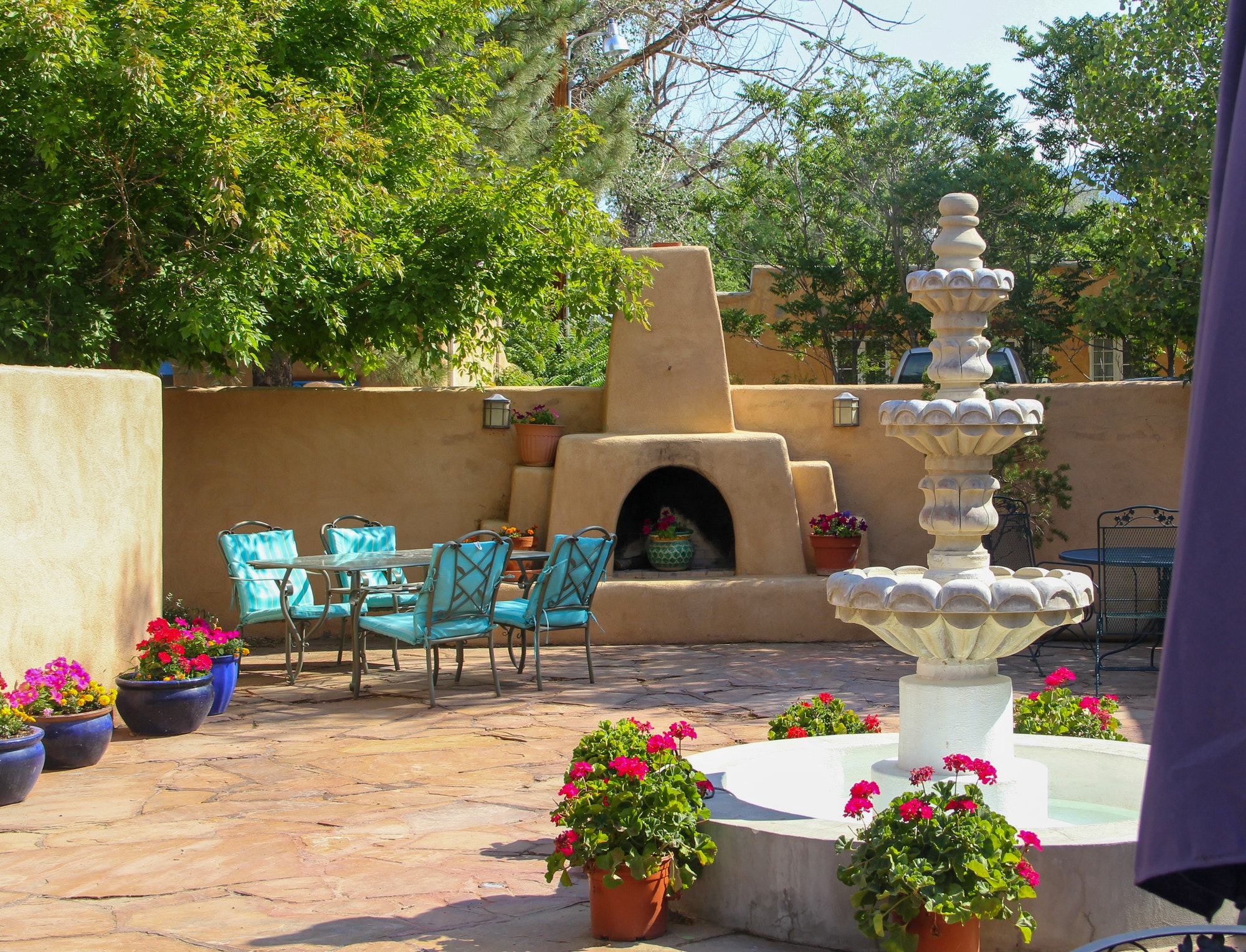 Beautiful traditional Taos New Mexico home back patio with flowers, fountain & colorful furniture